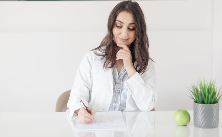 doctor takes notes at desk in office