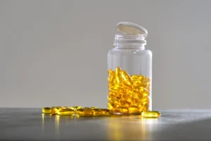 Glass jar of omega-3 capsules on table