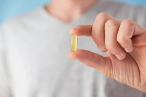 Man holds vitamin D capsule in hand