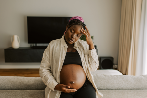 Pregnant woman in sports bra touches head