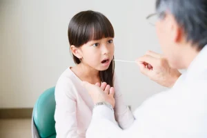Child with strep throat has throat swabbed by doctor