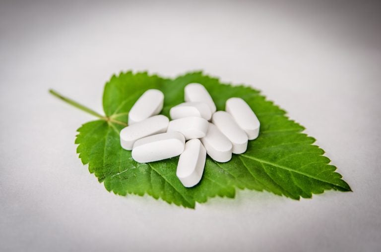 white supplement pills on leaf