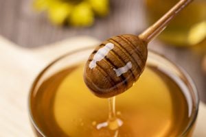 honey dripping from wand into glass jar