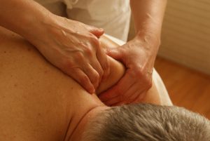 massage therapist focuses on man's shoulder