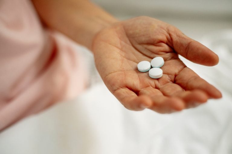 woman holds supplement tablets in hand