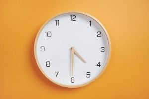 clock hangs on orange wall