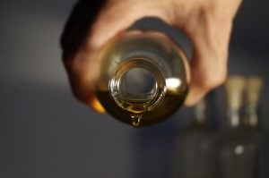 person pours olive oil from bottle
