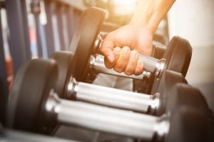 person pulls hand weight from rack at gym