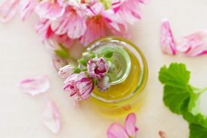 essential oil glass bottle with flowers scattered on table