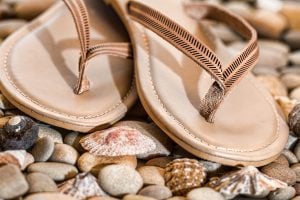 pair of beige flip flops on stones