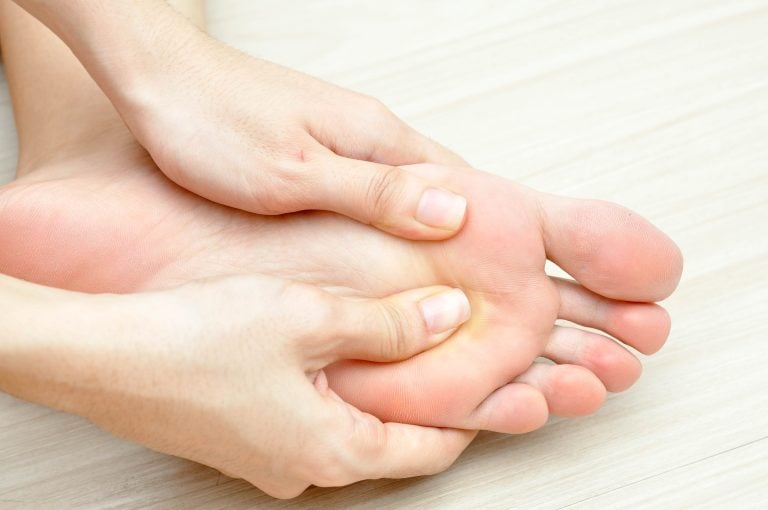 person holds sole of foot with hands
