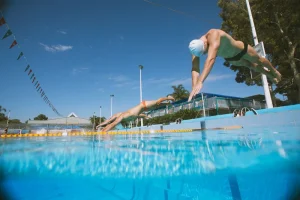 swimmers dive into pool