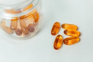 clear supplement capsules beside glass jar