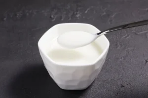 plain yogurt on spoon over white bowl