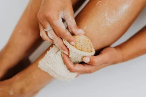 person uses salt scrub to exfoliate legs