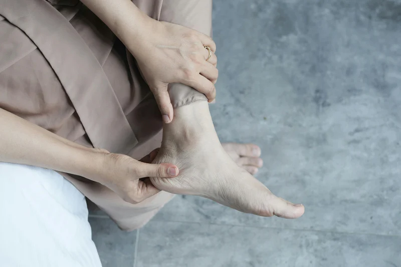 woman holds bare foot in pain