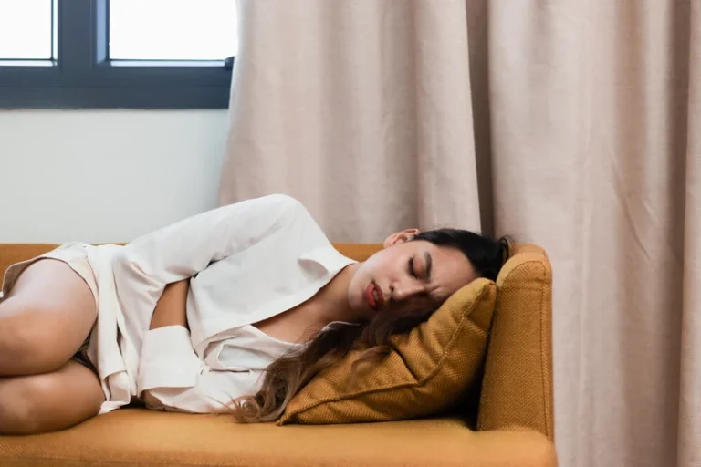 woman with menstrual cramps lies on sofa