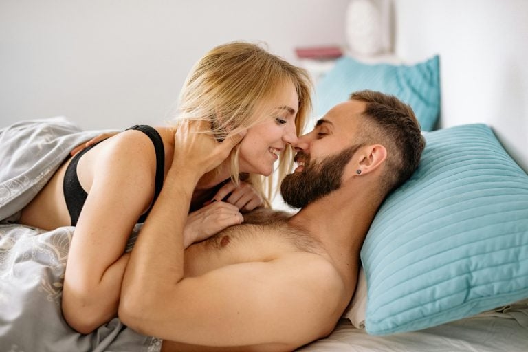 couple in bed smiles at each other